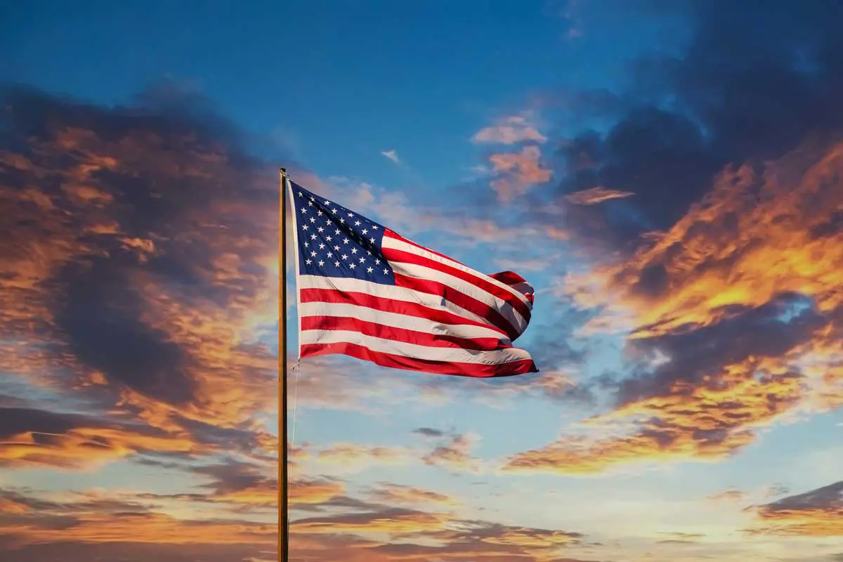 American flag waving against a colorful sunset sky.